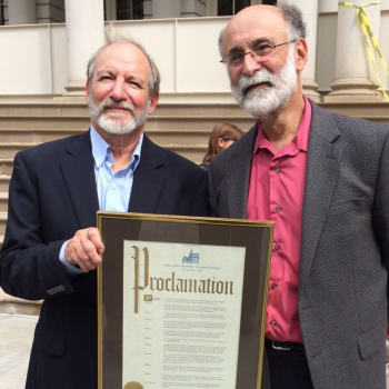 Michael & Robert Meeropol pose holding the 2015 NYC Proclamation fo "Ethel Rosenberg Day of Justice in the Borough of Manhattan" gathering