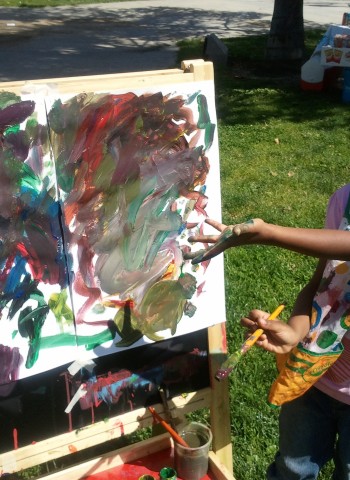 A beneficiary shows off her painting in a park setting