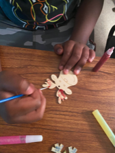 Beneficiary paints a Christmas ornament on a wooden table