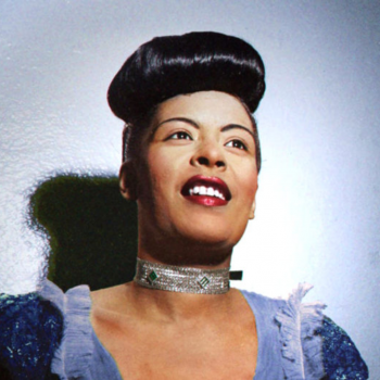 Close up photo of Billie Holiday wearing a lavender dress, hair styled up, and a diamond necklace. Gray background with spotlight on Billie.