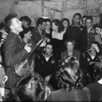 Pete Seeger entertaining Eleanor Roosevelt, honored guest at a racially integrated Valentine's Day party marking the opening of a canteen for the United Federal Workers of America, a trade union representing federal employees, in then-segregated Washington, D.C. Photographed by Joseph Horne for the Office of War Information, 1944. Credit: Wikimedia.