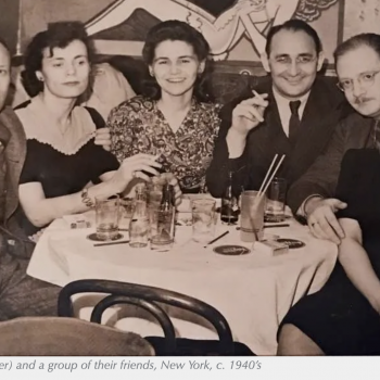 A sepia-tone photo of a group of six friends out to dinner in NYC circa 1940s. They wear suits and dresses, some smile for the picture, others just look at the camera. There are seated around a round table covered with a white tablecloth, empty bottles and glasses on the the tabletop. Three are smoking.