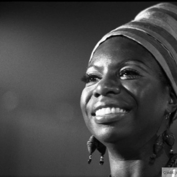 Black and white photo of Nina Simone smiling, close-up on her face.