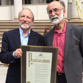 Michael and Robert Meeropol hold the framed Proclamation document before the steps of NYC's City Hall at the Sept 28, 2015 "Ethel Rosenberg Day of Justice in the Borough of Manhattan" ceremony