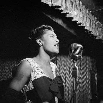 Billie Holiday sings at the mic on stage