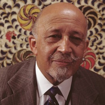 W. E. B. Du Bois in his elder years, poses for a photo against a colorful backdrop.