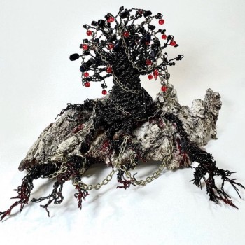 Sculpture "Strange Fruit" by Claudia McGinness crafted in the shape of a thorny tree growing roots, wrapped in chains. Materials include wire and red beads.