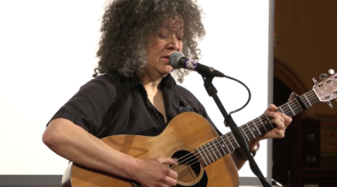 Pamela Means playing guitar and singing